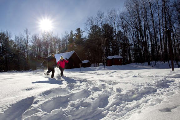 Deux personnes courant dans la neige devant un prêt à camper